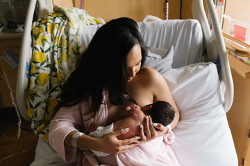 Woman feeding newborn daughter in hospital