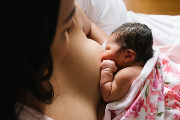 Woman feeding newborn daughter in hospital