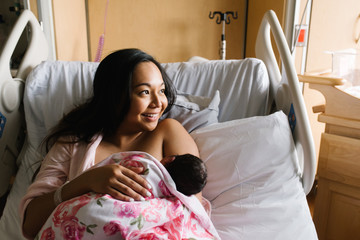 Woman feeding newborn daughter in hospital