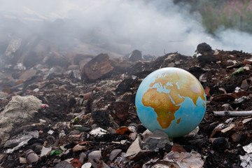 Concept to the problem of the environment - burning of garbage. Incineration plants are harmful to the environment. Planet earth is thrown into the trash. Garbage burns, smoke comes. Toxic dioxins.