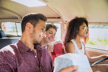 Mixed group of happy young people going on holiday in a van