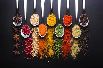 Foto op Canvas Spices and condiments for cooking on a black background © nehopelon