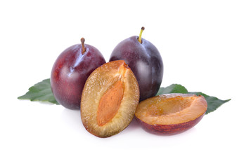 whole and half cut fresh prunes with leaf on white background