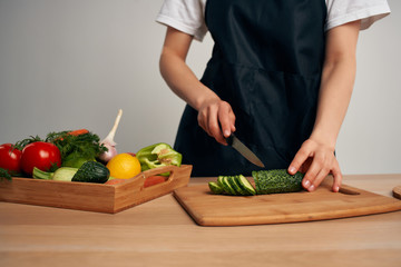 woman cuts cucumbers vegetables kitchen