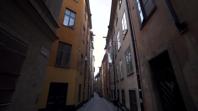 A steady glide cam footage moving forward on an empty street in the old town of Stockholm Sweden. Early morning in Gamla Stan, narrow street. Historical alley with some old Nordic houses.