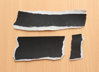 black torn paper texture on wood background, copy space.