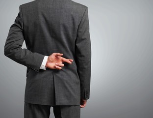 Businessman with his fingers crossed behind