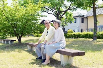 公園のベンチでほほ笑むシニア夫婦