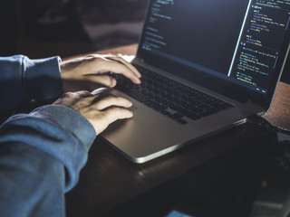 overhead hacker in the hood working with laptop and mobile phone typing text in dark room