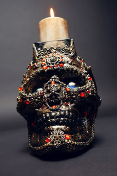 Skull decorated with colorful stones on black background