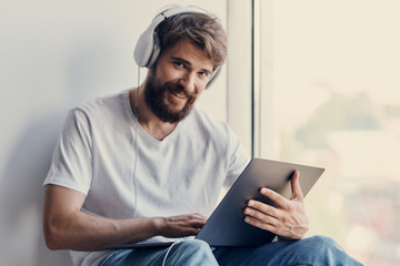 man in headphones with a tablet sits by the window