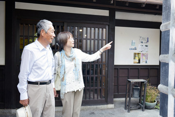 観光地で行き先を指さす旅行中のシニアカップル © tomoco_sozai