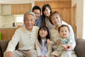リビングのソファで微笑む3世代家族