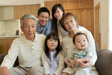 リビングのソファで微笑む3世代家族