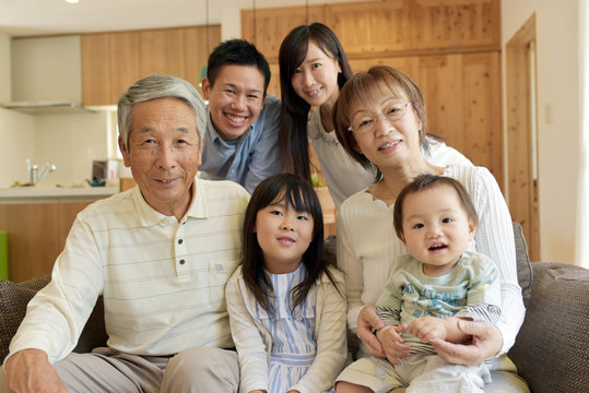 リビングのソファで微笑む3世代家族