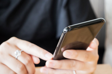 Woman with diamond ring on hand using smartphone in cafe restaurant