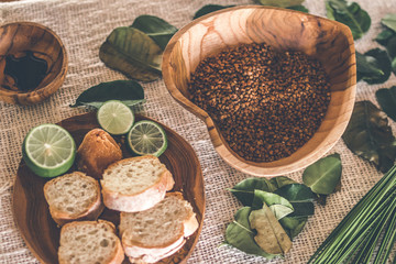 Teak Wooden bowl with buckwheat porridge on table. Traditional russian food. Lime and bread on the table.