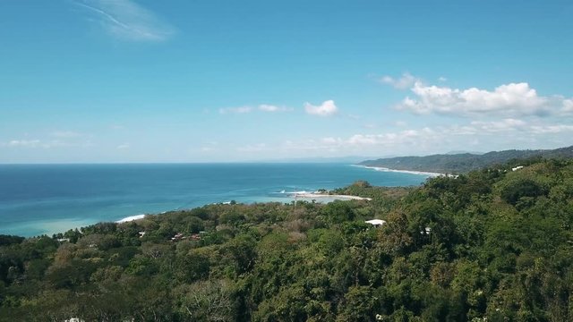 Drone shot of the beach of mal pais, costa rica, coming from the jungle towards the ocean. bright day, blue skies.