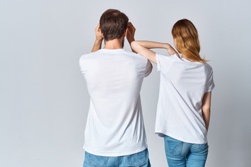 young couple in white t-shirts stand back to the camera logo