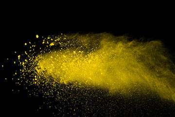 Abstract of yellow powder explosion on black background. Yellow powder splatted isolate. Colored...