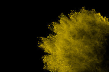Abstract of yellow powder explosion on black background. Yellow powder splatted isolate. Colored...