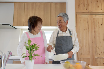キッチンで料理を楽しむシニア夫婦