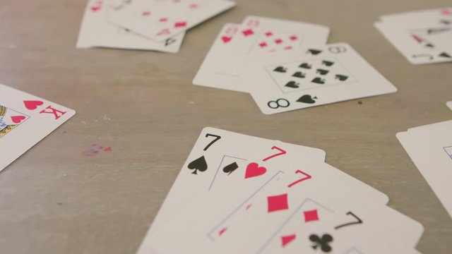 Playing cards are spread out in suites and sets on a table.