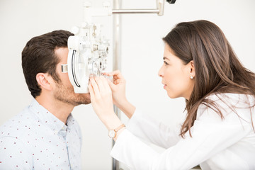 Focused optometrist adjusting panels of phoropter during eye checkup