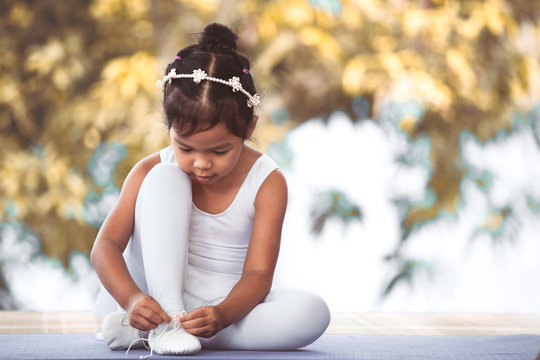 Cute Asian Child Girl Tying On Feet Pointe Shoes Preparing For Practicing A Ballet