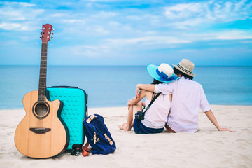 A baggage a guitar and a bag put on the beach background is Asia tourist enjoying at the sea on vacation.