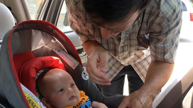 Dad Putting Infant In Car Seat For Safety On Road Trip