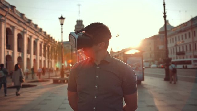 Guy in vr glasses in city trying to find something interesting additional information of this place. Virtual reality concept. Sunset or sunrise.