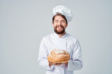 Cheerful cook holds a loaf of bread in his hand