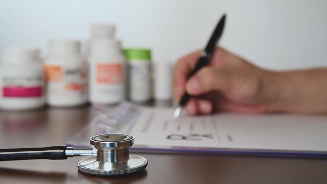 Male doctor hands writing rx prescription.