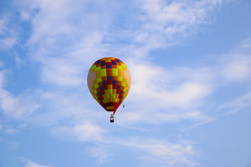 colorful hot air balloon against blue sky. hot air balloon is flying in white clouds. beautiful flying on hot air balloon