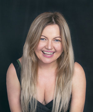Portrait of a Woman. A beautiful plump woman. Blonde. With a beautiful smile. On a black background.