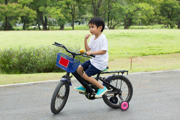 Fototapeta na wymiar Asian cute boy ride a bicycle at park green nature background.Side view Image.