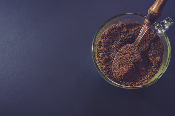 Spoon filled with coffee powder on black background.