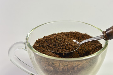 Spoon filled with coffee powder on white background.