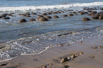 Pebbles and stones on wet sand in wave