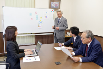 ホワイトボードを使って話をするシニアビジネスマン