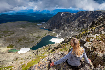 Naklejka premium Woman hiker enjoy the view at sunset mountain peak cliff. Stylish woman hiking. Travel Lifestyle and survival concept rear view.