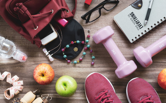 Woman active healthy lifestyle concept. Creative flat lay of sport and fitness equipments  with woman accessories, apples, bottle of waters, sports shoes and dumbbells.