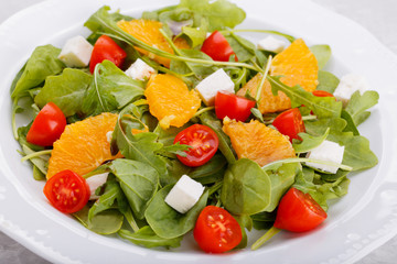 Healthy salad with feta cheese tomato orange and balsamic dressing, close up top view