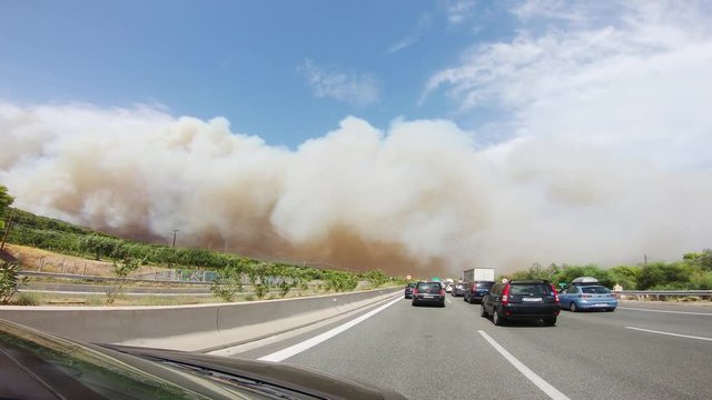 View from a car driving on the highway approaching Kineta and entering into a smoke cloud from the wildfire. One of the largests wildfires of Attica during that summer in Greece.