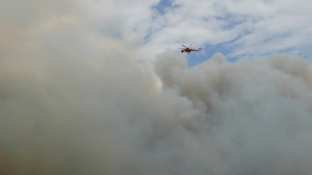 During the wildfires in Attica Greece. View of the smoke from the highway and Skycrane helicopter firefighting.