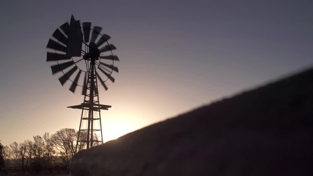 Farm wind pump turns in the winds as the sun begins to set.