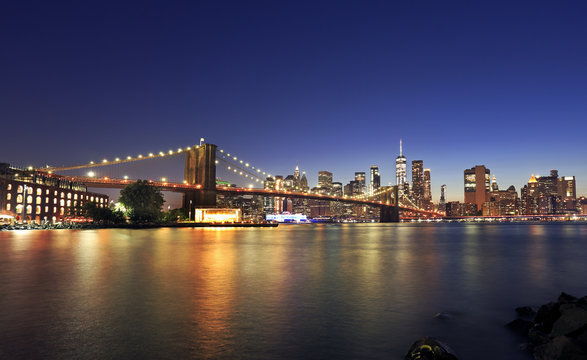 Panorama of Brooklyn Bridge and New York City (Lower Manhattan) with lights and reflections at dusk, USA
