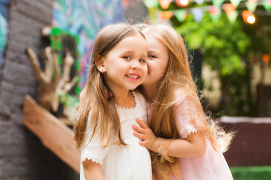 two smiling little girls of the girlfriend in the summer outdoors. kids celebrate birthday party together

