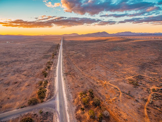 Rural highway leading into Ikara-Flinders Ranges national park at sunset - aerial landscape